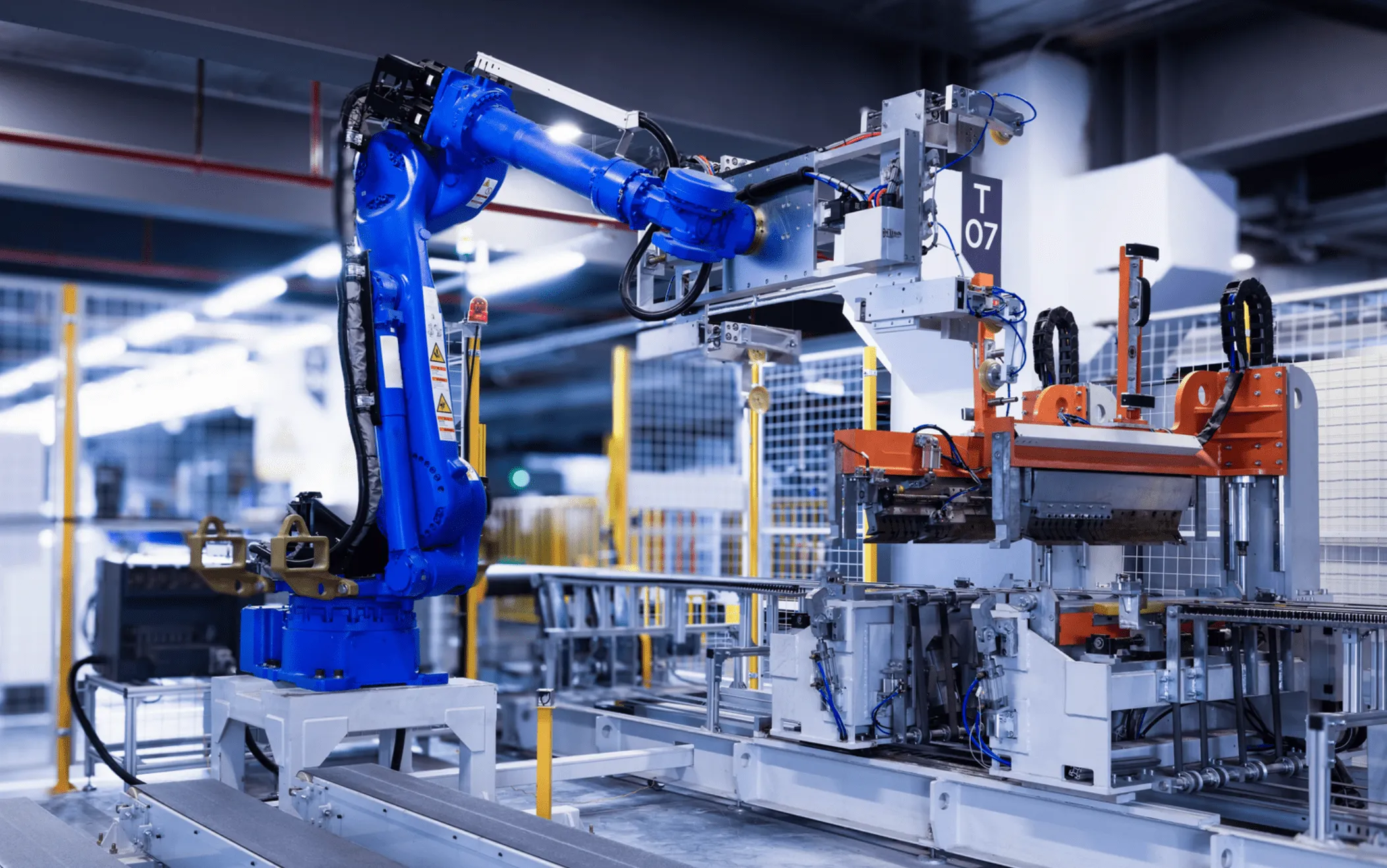 Blue robotic arm operating automated machinery in a modern factory setting.
